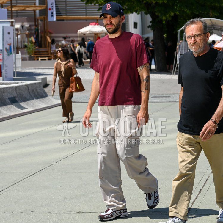 Summer/spring men's coordinate and outfit with New Era navy lettered baseball cap, plain red t-shirt, plain white cargo pants, and white low-cut sneakers.