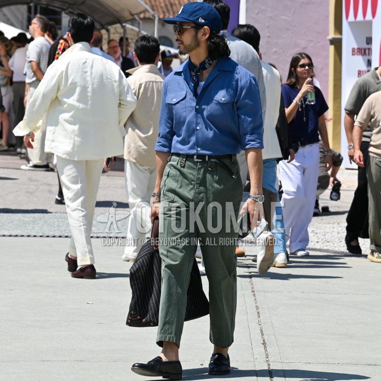 New Era navy lettered baseball cap, black eyewear sunglasses, solid blue bandana/neckerchief, solid blue shirt, solid white tank top, solid black leather belt, solid olive green cargo pants, solid olive green ankle pants, black coin loafer leather shoes, solid black briefcase/handbag, summer/spring men's coordinate/outfit.