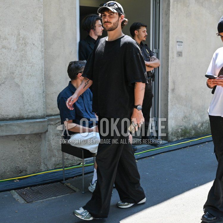 グレー無地のベースボールキャップ、黒無地のサングラス、黒無地のTシャツ、黒無地のスラックス、白・グレーローカットのスニーカーを合わせた春夏のメンズコーデ・着こなし。