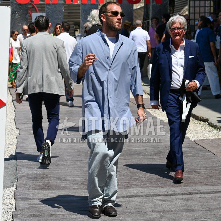 Men's spring/summer coordinate and outfit with clear solid sunglasses, stand collar solid blue shirt, solid white t-shirt, solid gray denim/jeans, and brown leather shoes.