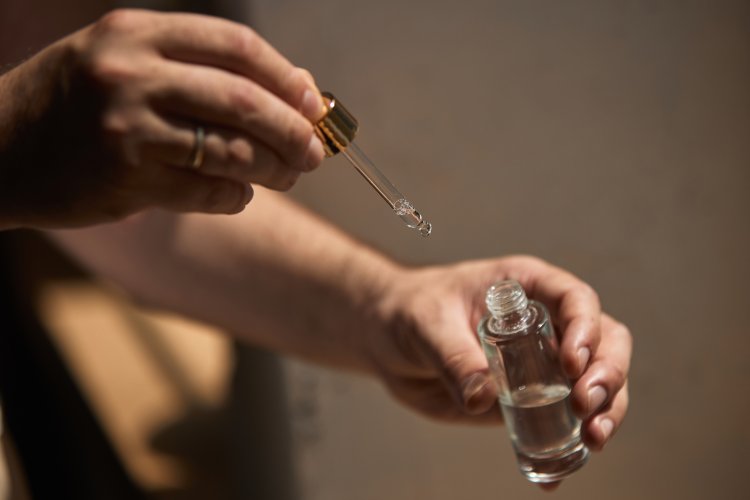 Hybrid skincare. Hands holding glass dropper and small bottle with clear liquid