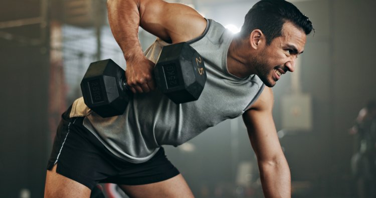 Man, dumbbell and weightlifting in fitness, workout or arm exercise on bench at indoor gym. Serious male person, bodybuilder or athlete lifting weight in sports training, health and wellness at club