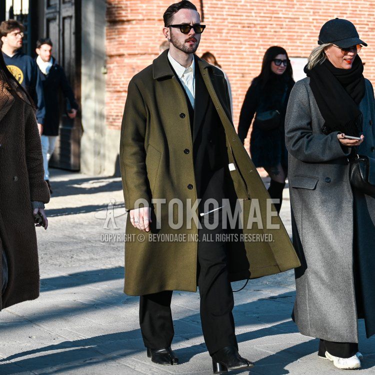 Men's fall/winter outfit and outfit with plain black sunglasses, plain olive green stainless steel collared coat, plain white shirt, black boots, and plain black suit.