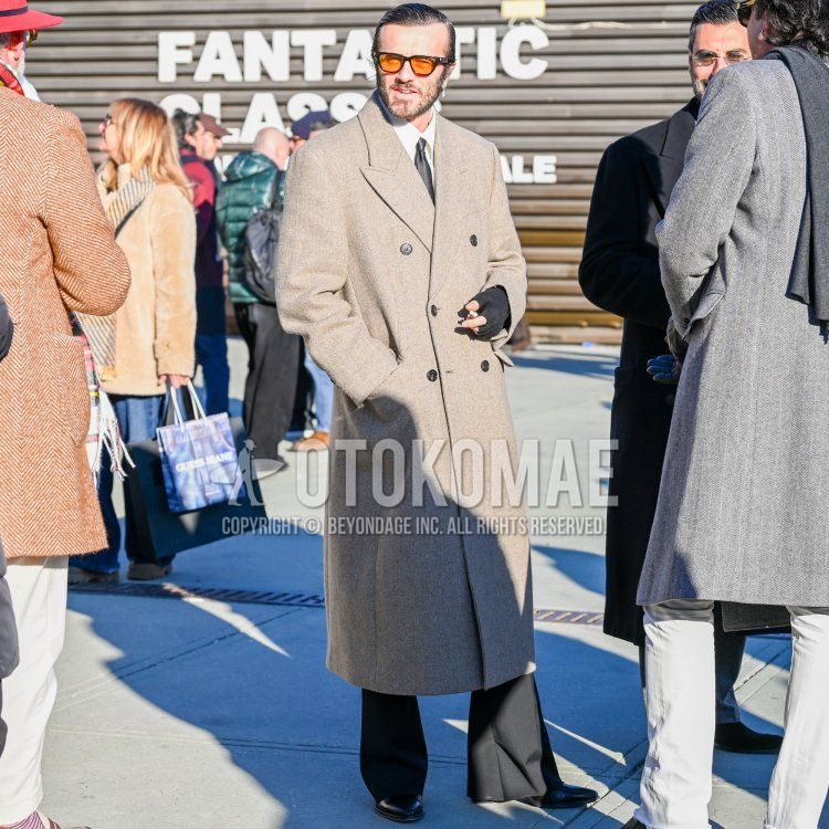 Men's fall/winter outfit/clothing with plain black glasses, plain gray chester coat, plain white shirt, plain black slacks, black boots and plain black tie.