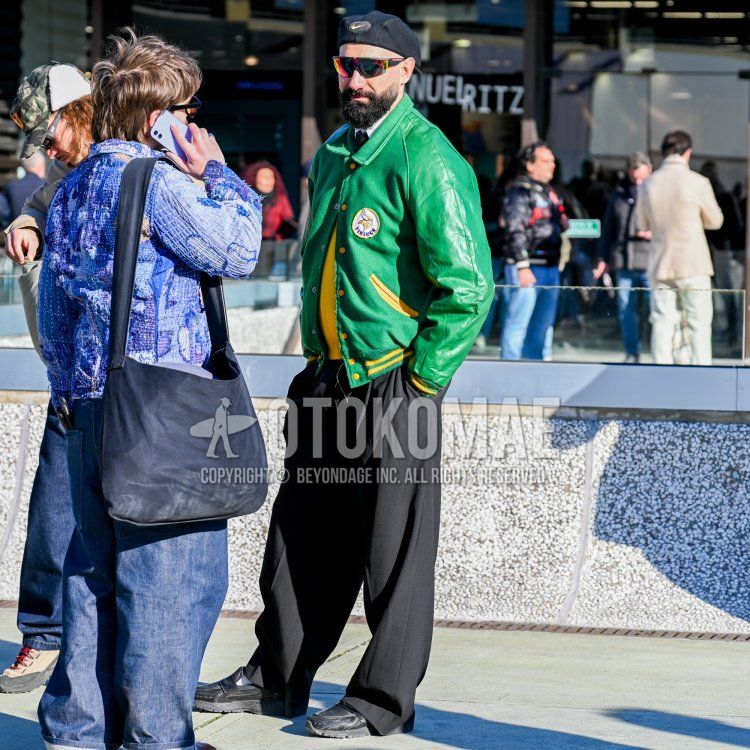 Men's fall/winter coordinate and outfit with Nike black one-pointed cap, multi-colored solid sunglasses, green one-pointed stadium jacket, solid yellow sweater, solid white shirt, solid black wide-leg pants, black slip-on sneakers, and solid black tie.