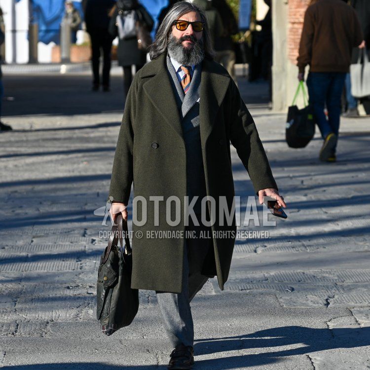 Winter men's coordinate and outfit with plain black/brown sunglasses, plain olive green chester coat, black leather shoes, plain black clutch bag/second bag/drawstring, plain gray suit, and orange tie tie.