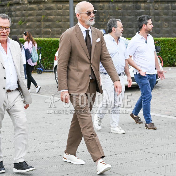 Men's fall/spring/summer outfit with clear solid sunglasses, solid white shirt, solid brown leather belt, white low-cut sneakers, solid brown suit, and solid brown tie.