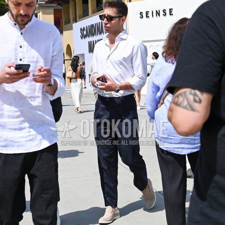 Men's spring and summer coordinate and outfit with plain black sunglasses, plain white shirt, plain navy slacks, and beige slip-on sneakers.