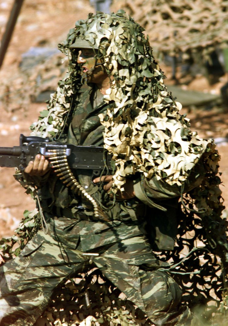 A GREEK SOLDIER IN CAMOUFLAGE UNIFORM TAKES COVER