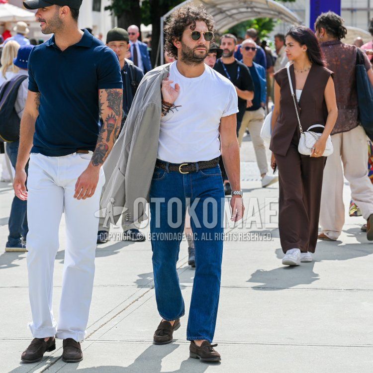 Spring/summer men's outfit with solid gold sunglasses, solid gray tailored jacket, solid white t-shirt, solid brown mesh belt, solid brown leather belt, solid blue denim/jeans, solid brown tassel loafers leather shoes, brown suede shoes leather shoes. Outfit.