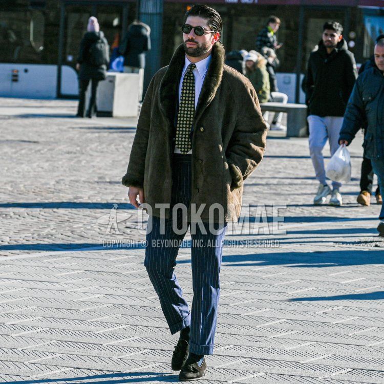 Winter men's outfit with black/brown tortoiseshell sunglasses, solid brown boa jacket/coat, solid white shirt, navy/white striped slacks, solid navy socks, brown tassel loafer leather shoes, and green/yellow dot tie.