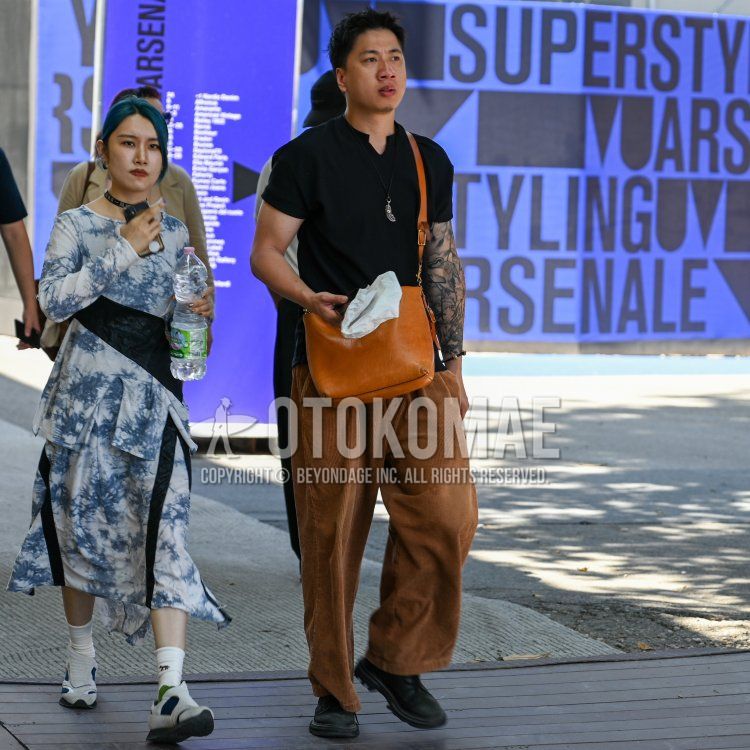 バンドカラーの黒無地のV ネック、黒無地のTシャツ、ブラウン無地の冬パンツ(コーデュロイ,ベロア)、黒プレーントゥの革靴、オレンジ無地のショルダーバッグを合わせた春夏のメンズコーデ・着こなし。
