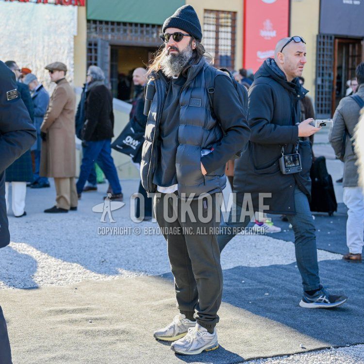 Solid black knit cap, solid black Boston sunglasses, solid black down vest, solid gray sweatshirt, solid gray jogger pants/ribbed pants, solid gray sweatpants, New Balance 1906R gray low cut sneakers, solid black backpack, fall/winter Men's Codes and Outfits for Fall/Winter.