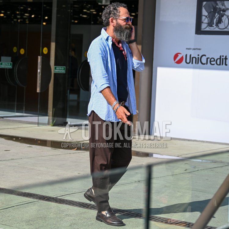 クリア無地のサングラス、レッドペイズリーのバンダナ/ネッカチーフ、ブルーストライプのシャツ、ネイビー無地のTシャツ、ブラウン無地のスラックス、ブラウン無地のアンクルパンツ、ブラウンコインローファーの革靴を合わせた春夏のメンズコーデ・着こなし。