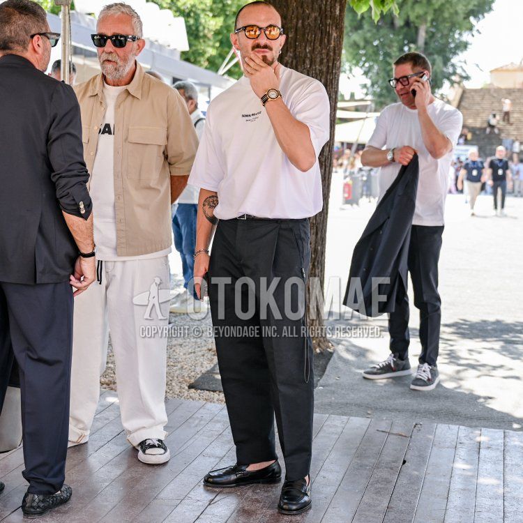 Summer/spring men's coordinate and outfit with black tortoiseshell sunglasses, white lettered t-shirt, plain black leather belt, plain black slacks, plain black pleated pants, and black coin loafer leather shoes.