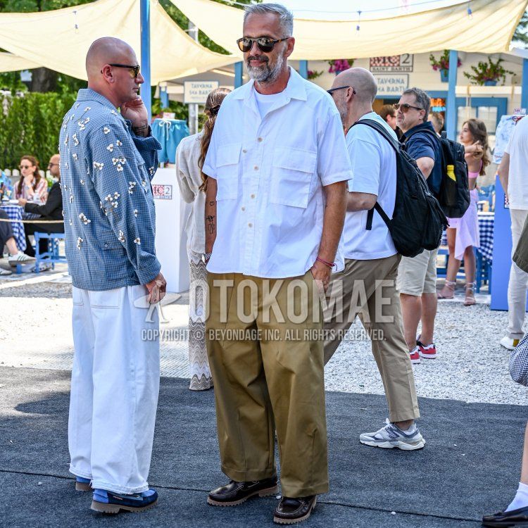 Summer/spring men's coordinate and outfit with black tortoiseshell sunglasses, plain white shirt, plain white t-shirt, plain beige chinos, plain beige pleated pants, brown moccasins/deck shoes leather shoes.