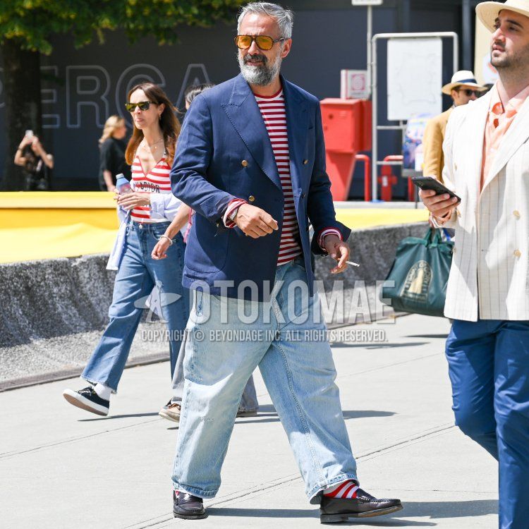 Men's fall/spring outfit with solid orange/black sunglasses, solid navy tailored jacket, solid red/white t-shirt, solid light blue denim/jeans, solid red/white socks, and brown coin loafer leather shoes.
