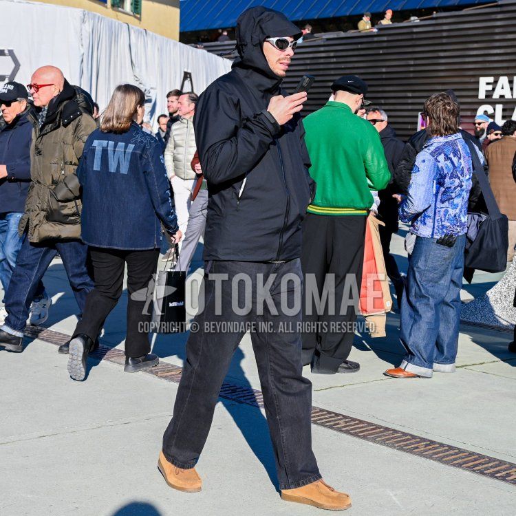 Men's fall/winter outfit with plain black sunglasses, plain black windbreaker, plain gray denim/jeans, and suede beige boots.