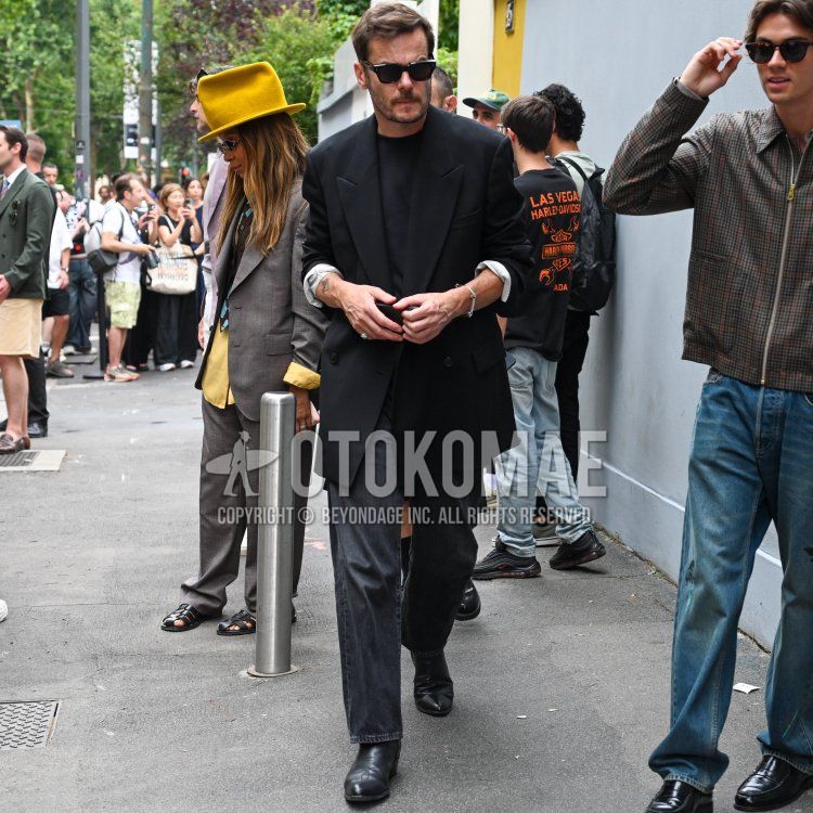 Summer/spring men's coordinate and outfit with plain black sunglasses, plain black tailored jacket, plain black t-shirt, plain black/dark gray denim/jeans, and black boots.