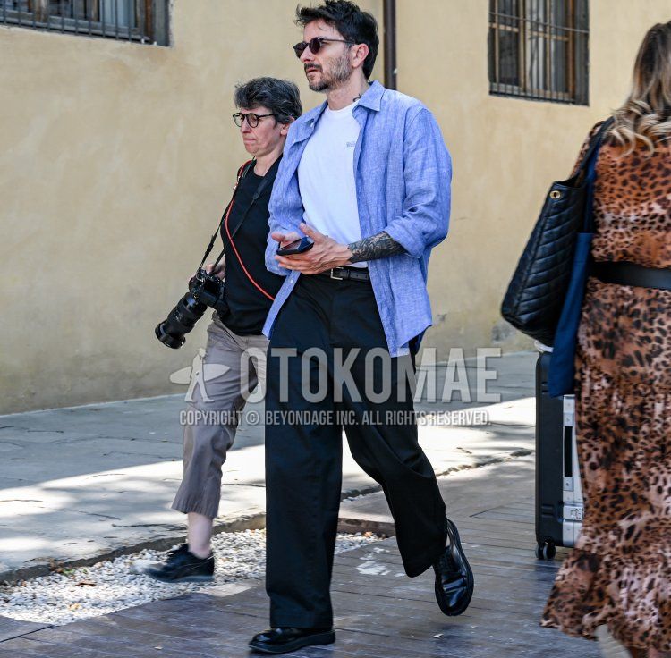 Men's summer/spring outfit with plain black sunglasses, plain blue denim/chambray shirt, white one-pointed t-shirt, plain black leather belt, plain black slacks, and black plain-toe leather shoes.