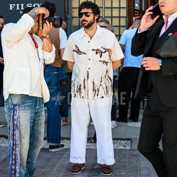 A summer outfit for mature men featuring a short-sleeved, open-collar shirt with a bird-and-plant pattern on an off-white background