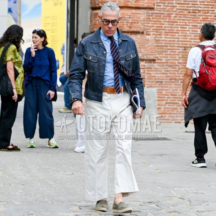A men's outfit for fall and spring featuring plain black glasses, a plain navy denim jacket, a plain light blue shirt, a plain brown leather belt, plain white dress pants, plain gray espadrilles, and a plain blue-and-red tie.